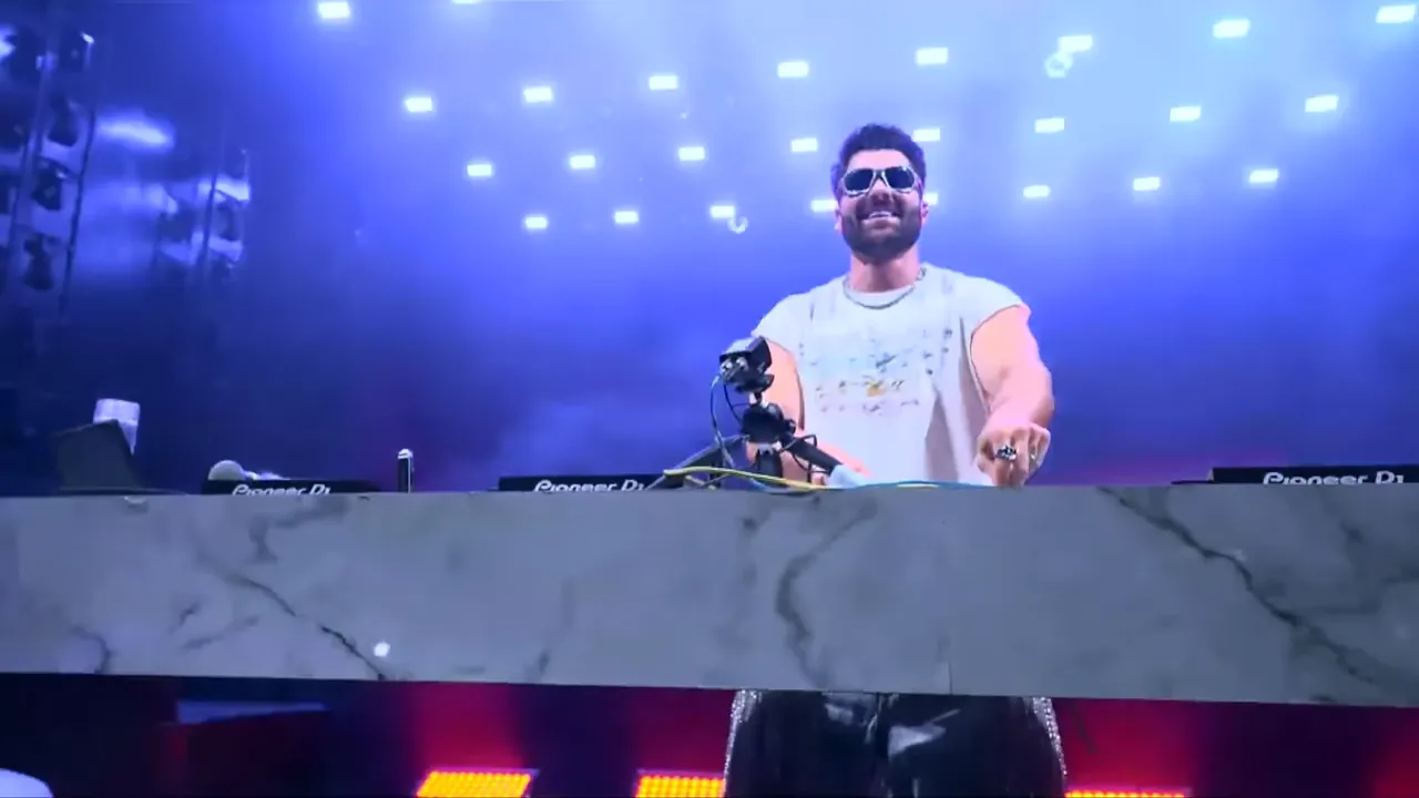 Alok smiling at the decks under the stage lights on Copacabana Beach, Rio